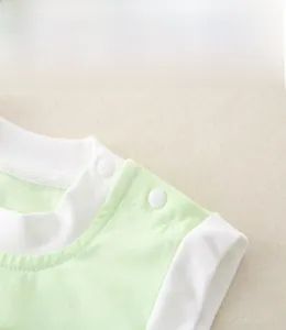 Detailed view of shoulder snap buttons on a soft green cotton baby romper for easy dressing