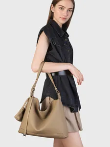 Grande borsa tote minimalista in pelle kaki presentata come borsa a spalla su modella