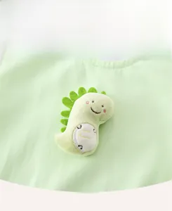 Close-up of a 3D plush green dinosaur accessory on soft cotton baby romper