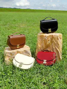 Elegant half-moon leather shoulder bags in four colors displayed on a grassy lawn