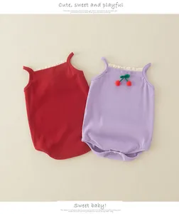 Flat lay of ribbed cotton baby bodysuits with lace trim and cherry embroidery detail