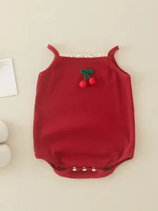 Sleeveless red cotton baby romper with lace trim and cherry detail on cream background