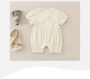 Flat lay view of a soft yellow baby summer romper with cute puff sleeves on beige fabric