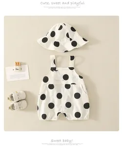 Flat lay of baby sleeveless romper and sun hat set with black polka dots on cream cotton