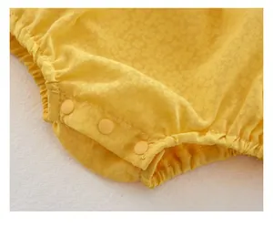 Detailed macro view of yellow floral baby bodysuit featuring functional resin snap buttons