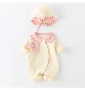 Detail of baby cotton romper with pink bunny collar and matching bonnet in soft light yellow