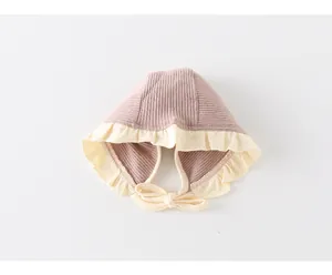 Detail of baby knit bonnet with cream ruffle trim and adjustable soft chin strap