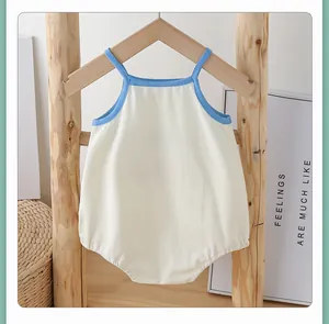 Detailed view of baby sleeveless cotton romper with blue trim hanging on wooden hanger