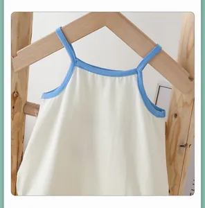 Detail of baby cotton bodysuit with blue trim and wooden hanger on a clean background