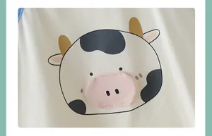 Macro detail of cartoon cow print and 3D applique on cotton baby bodysuit