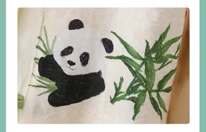 Detailansicht der Panda- und Bambusblatt-Stickerei auf dem chinesischen Baby-Strampler