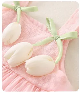 Detail of pink toddler dress neckline with green satin bow and white 3D tulip flowers