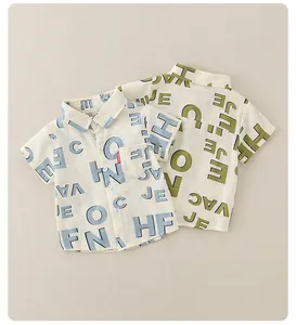 Nahaufnahme von beigen Kinder-Kurzarmhemden mit grünen und grauen Buchstabendrucken