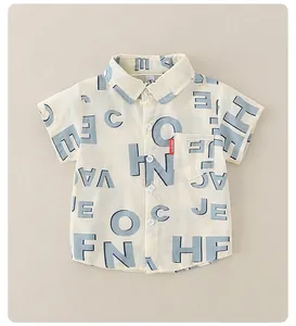 Detailansicht eines beigen Kinderhemds mit blauem Buchstabendruck und Fashion-Tag