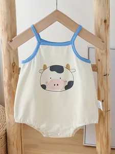 Cotton baby bodysuit with cute cartoon cow print and blue trim on a wooden background