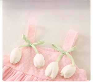 Detail of pink plaid baby dress with green satin bow and white tulip floral accents