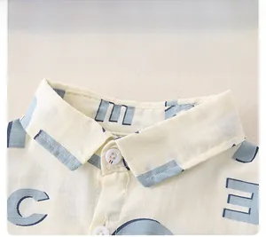 Detailaufnahme des Kinderhemdkragens mit blauem Buchstabendruck und weißen Knöpfen