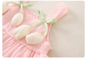 Detail view of pink toddler dress featuring green satin straps and white 3D tulip accents