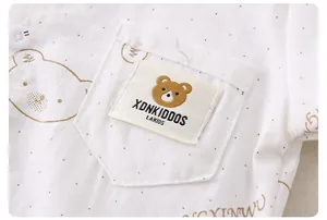 Detail of kids cream shirt showing golden polka dots, bear prints and a woven pocket label