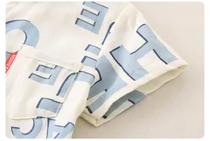 Nahaufnahme der beigen Baumwollshirt-Stofftextur mit blauem Buchstabendruck und Etikett