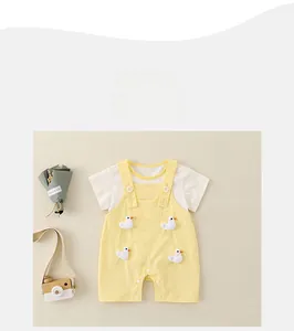 Détail d'ensemble d'été bébé avec t-shirt blanc et salopette jaune à motif canard