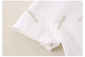 Close-up of white cotton fabric detail with brown dots and artistic letter printing