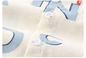 Makroaufnahme von atmungsaktivem beigem Leinenstoff mit blauem Druck und Dekoknöpfen