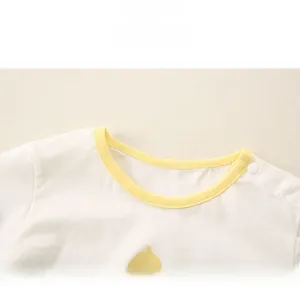 Détail d'un t-shirt bébé en coton avec imprimé canard et boutons pression à l'épaule