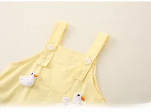 Détail de la salopette bébé jaune en coton avec petits canards en peluche et boutons