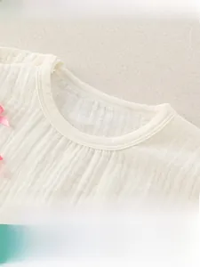 Vue détaillée de l'encolure en coton pour bébé avec nœud rose et bouton pression
