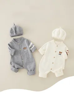Flat lay of baby knit rompers in grey and beige with matching berets and bear embroidery