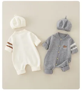 Detail of knitted baby rompers with bear embroidery and matching hats on beige background
