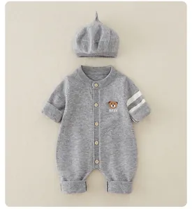 Close-up of knit baby romper with wooden buttons, bear embroidery, and matching hat