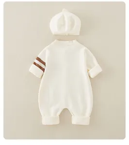 Detail of baby knitted romper and beret set in off-white cotton with brown sleeve stripes