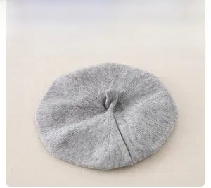 Detail showing soft light grey knitted baby beret hat with a small top loop handle
