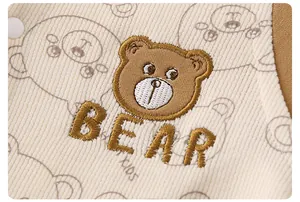 Detailed close-up of cute bear embroidery and text on baby's corduroy jumpsuit