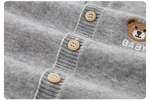 Close-up of grey baby knit cardigan featuring wooden buttons and teddy bear embroidery