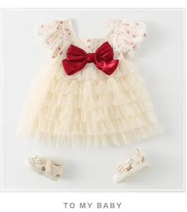 Détail d'une robe en coton pour bébé avec fleurs, nœud rouge et sandales assorties