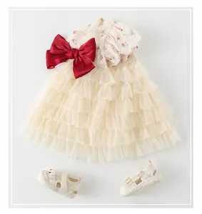 Détail de robe fleurie pour bébé fille avec nœud en soie rouge et sandales assorties