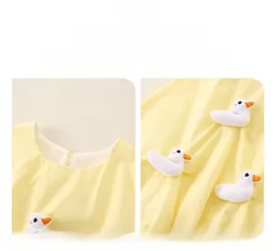 Detail of yellow toddler top featuring 3D white plush ducklings and round neckline