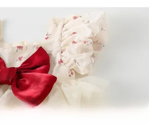 Détail de robe fleurie pour bébé fille avec nœud en velours rouge et manches bouffantes