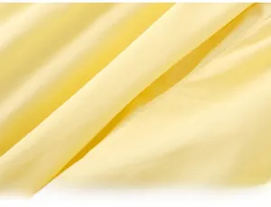 Close-up of soft yellow cotton fabric texture showing fine weave and premium material