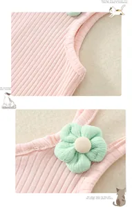 Détail d'un body rose côtelé pour bébé avec une décoration de fleur en tissu vert