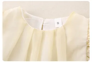 Detail of baby girl yellow top with pleated neckline and size S label on fabric
