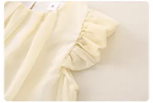 Detail of ruffled flutter sleeves and soft chiffon texture on light yellow baby top