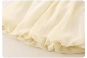 Detail of baby girl outfit showing cream chiffon fabric texture and puffy hemline
