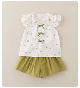 Detail von weißem Rüschen-Top mit grünen Schleifen und passenden grünen Shorts Set