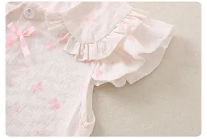 Detail von Mädchen-Sommeroberteil mit rosa Schleifendruck und Rüschenärmeln