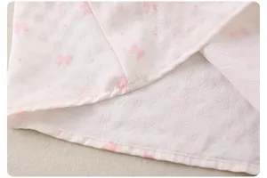 Detailaufnahme des Mädchen-Sommeroutfits mit rosa Schleifen und Punktmuster
