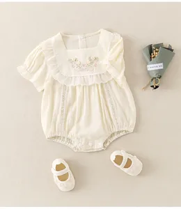 Detail of baby girl floral embroidered romper with matching lace-trimmed shoes